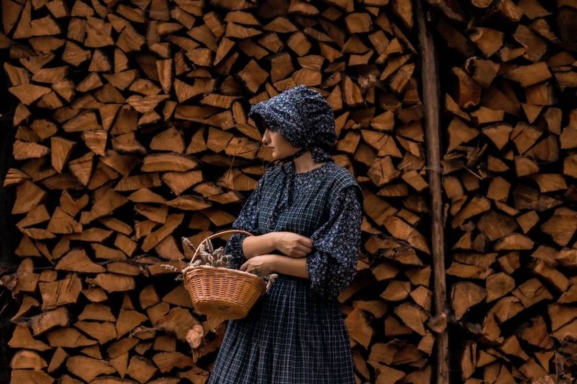 Colonial Era woman in fornt of Log background
